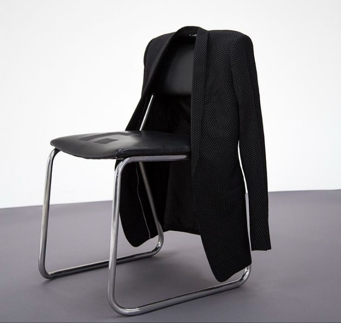 A dark jacket draped over a modern chair